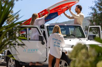 Salon lumineux avec canapé blanc, table basse, bureau près de la fenêtre et vue sur un jardin verdoyant.
