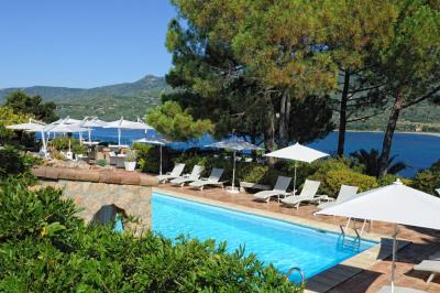 Salon lumineux avec canapé blanc, table basse, bureau près de la fenêtre et vue sur un jardin verdoyant.