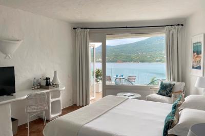 Salon lumineux avec canapé blanc, table basse, bureau près de la fenêtre et vue sur un jardin verdoyant.