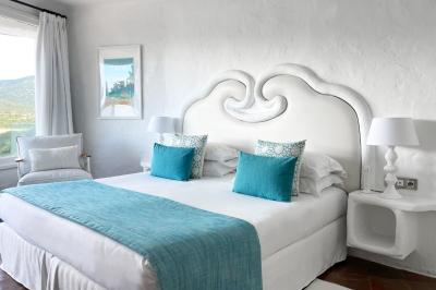 Salon lumineux avec canapé blanc, table basse, bureau près de la fenêtre et vue sur un jardin verdoyant.