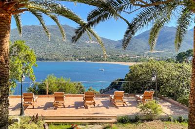 Salon lumineux avec canapé blanc, table basse, bureau près de la fenêtre et vue sur un jardin verdoyant.