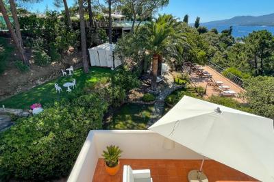 Salon lumineux avec canapé blanc, table basse, bureau près de la fenêtre et vue sur un jardin verdoyant.