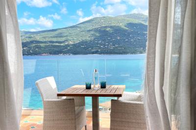 Salon lumineux avec canapé blanc, table basse, bureau près de la fenêtre et vue sur un jardin verdoyant.
