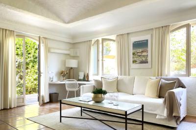 Salon lumineux avec canapé blanc, table basse, bureau près de la fenêtre et vue sur un jardin verdoyant.