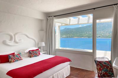 Salon lumineux avec canapé blanc, table basse, bureau près de la fenêtre et vue sur un jardin verdoyant.