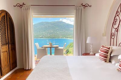 Salon lumineux avec canapé blanc, table basse, bureau près de la fenêtre et vue sur un jardin verdoyant.
