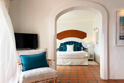 Salon lumineux avec canapé blanc, table basse, bureau près de la fenêtre et vue sur un jardin verdoyant.