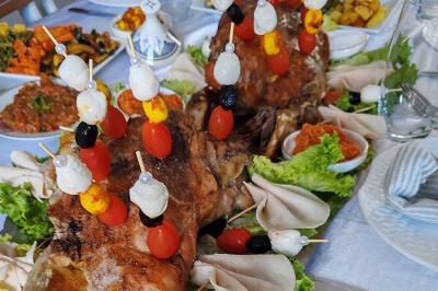 Plat de viande rôtie décorée de brochettes de légumes et servi avec des accompagnements variés sur une table dressée.