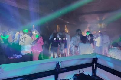 Un DJ mixant de la musique sur une table de mixage dans une salle éclairée par des lumières violettes.