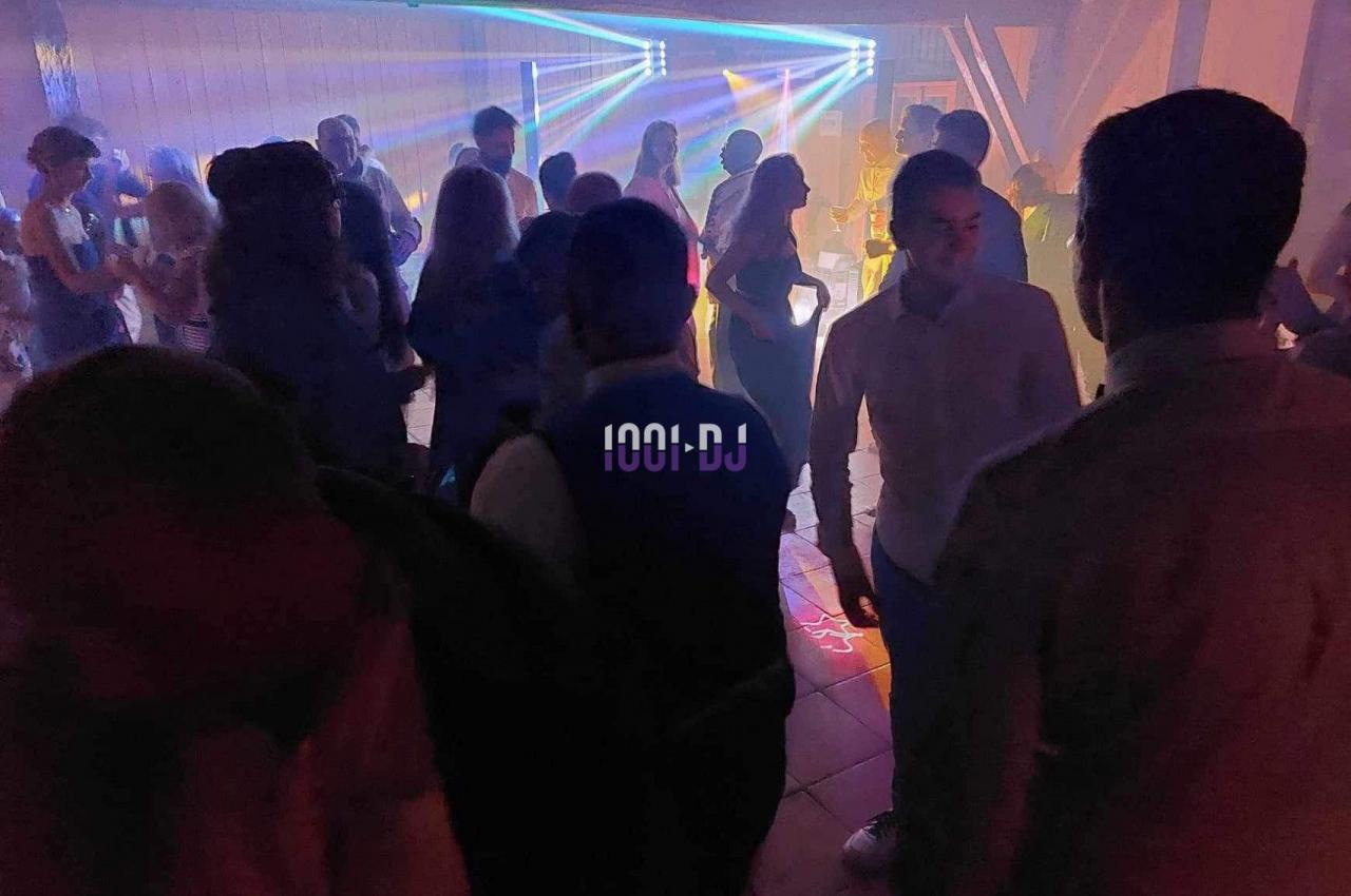 Personnes dansant dans une salle sombre avec des jeux de lumière colorés et une ambiance festive.