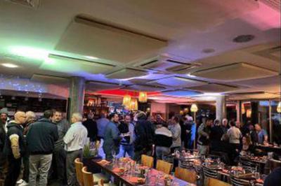 Étang entouré de végétation avec des montagnes en arrière-plan sous un ciel bleu parsemé de nuages.