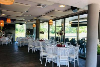 Étang entouré de végétation avec des montagnes en arrière-plan sous un ciel bleu parsemé de nuages.