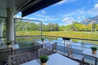 Étang entouré de végétation avec des montagnes en arrière-plan sous un ciel bleu parsemé de nuages.