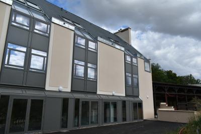 Bâtiment circulaire en pierre avec une pelouse et des arbres, sous un ciel partiellement nuageux.