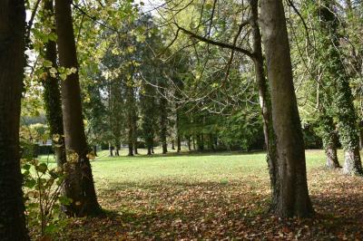 Bâtiment circulaire en pierre avec une pelouse et des arbres, sous un ciel partiellement nuageux.