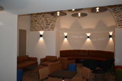 Bâtiment circulaire en pierre avec une pelouse et des arbres, sous un ciel partiellement nuageux.