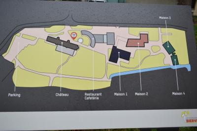 Bâtiment circulaire en pierre avec une pelouse et des arbres, sous un ciel partiellement nuageux.