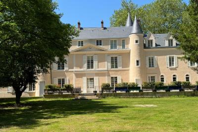 Bâtiment circulaire en pierre avec une pelouse et des arbres, sous un ciel partiellement nuageux.