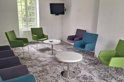 Bâtiment circulaire en pierre avec une pelouse et des arbres, sous un ciel partiellement nuageux.