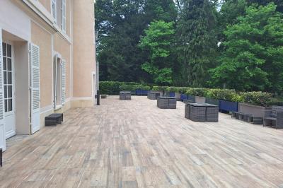 Bâtiment circulaire en pierre avec une pelouse et des arbres, sous un ciel partiellement nuageux.