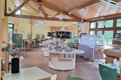 Bâtiment circulaire en pierre avec une pelouse et des arbres, sous un ciel partiellement nuageux.