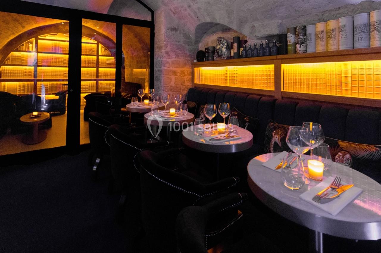 Salle de restaurant élégante avec tables dressées, éclairage chaleureux et murs en pierre apparente.