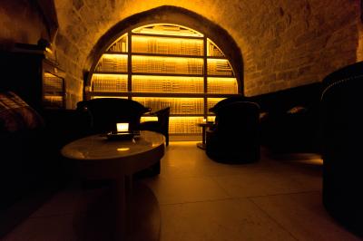 Verre de cognac, bouteille en arrière-plan, cigare allumé posé sur un cendrier et briquet sur une table en marbre.