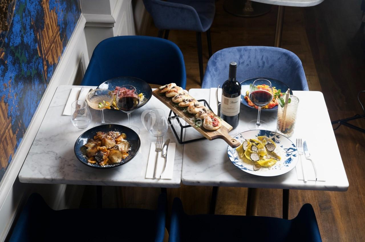 Table dressée avec des plats variés, dont des fruits de mer, des viandes, un plateau de brochettes, et des verres de vin.