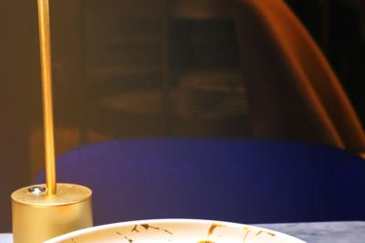 Saucisson sec artisanal suspendu dans un filet devant des bouteilles de vin en arrière-plan flou.