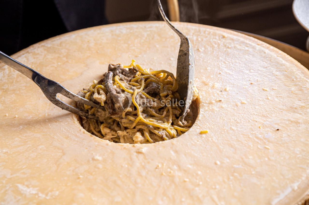 Pâtes crémeuses mélangées avec des morceaux de viande dans une meule de fromage.