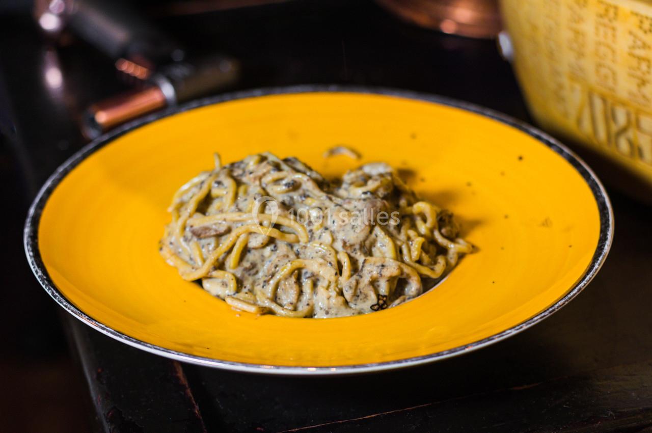 Assiette jaune contenant des pâtes en sauce crémeuse, posée sur une table sombre.