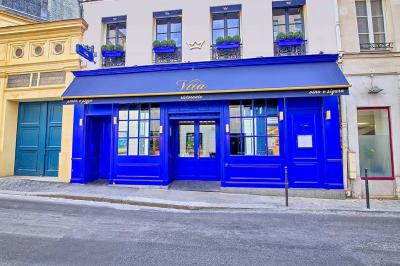 Saucisson sec artisanal suspendu dans un filet devant des bouteilles de vin en arrière-plan flou.