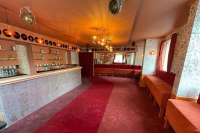 Salle avec bar, banquettes rouges, décor rétro, disques vinyles au mur et éclairage chaleureux.