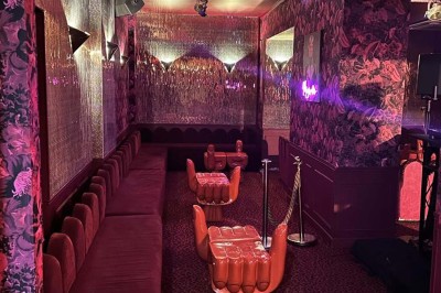 Salle avec bar, banquettes rouges, décor rétro, disques vinyles au mur et éclairage chaleureux.