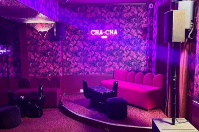 Salle avec bar, banquettes rouges, décor rétro, disques vinyles au mur et éclairage chaleureux.