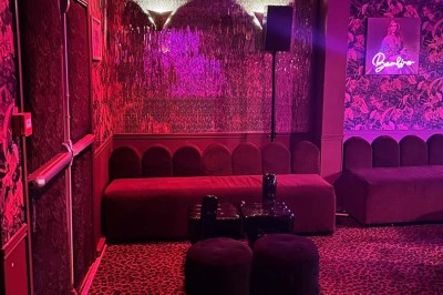 Salle avec bar, banquettes rouges, décor rétro, disques vinyles au mur et éclairage chaleureux.