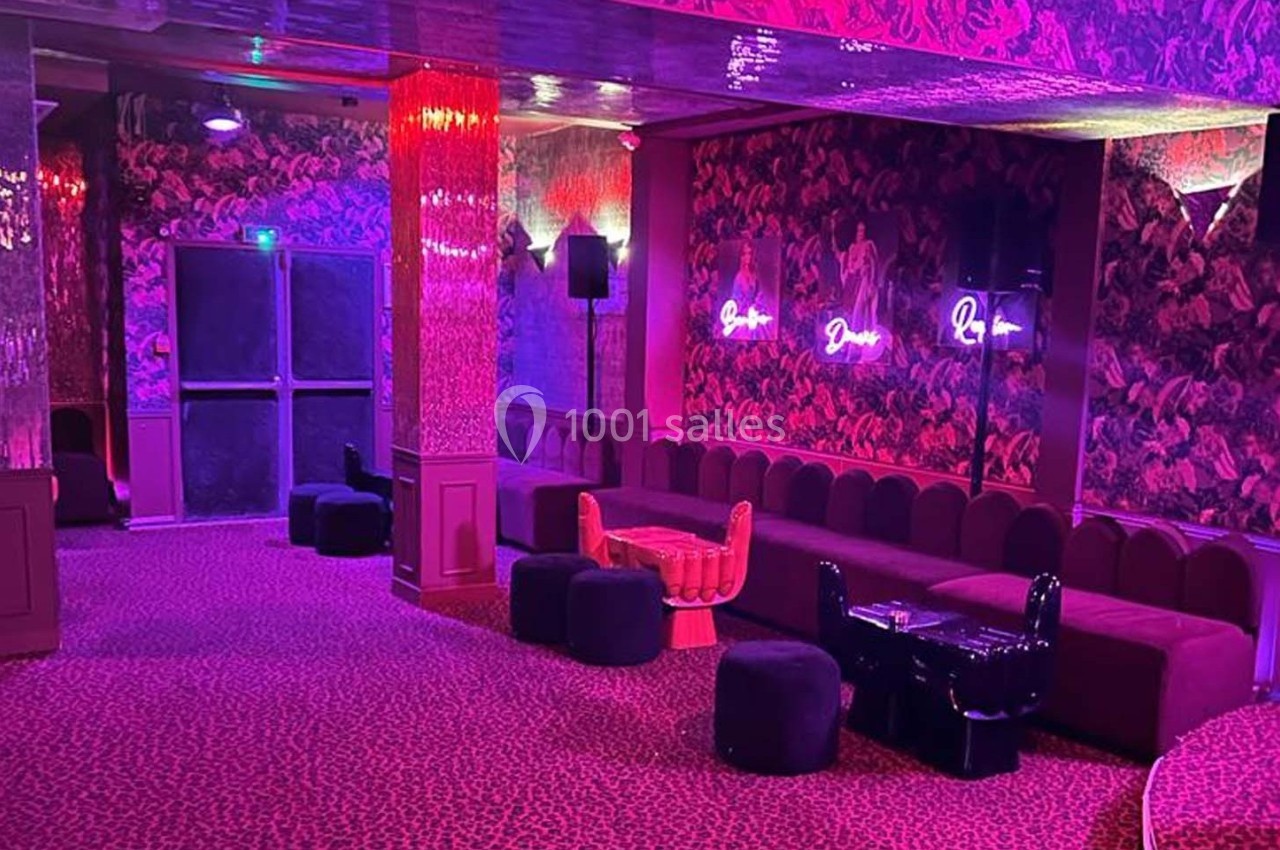 Salle colorée avec banquettes, poufs, murs ornés de motifs et néons lumineux, ambiance tamisée.