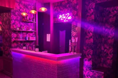 Salle avec bar, banquettes rouges, décor rétro, disques vinyles au mur et éclairage chaleureux.