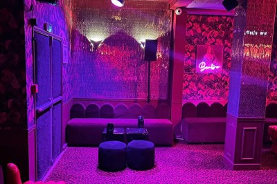 Salle avec bar, banquettes rouges, décor rétro, disques vinyles au mur et éclairage chaleureux.