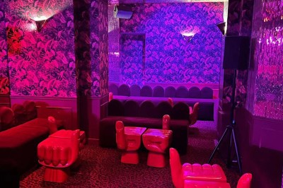 Salle avec bar, banquettes rouges, décor rétro, disques vinyles au mur et éclairage chaleureux.