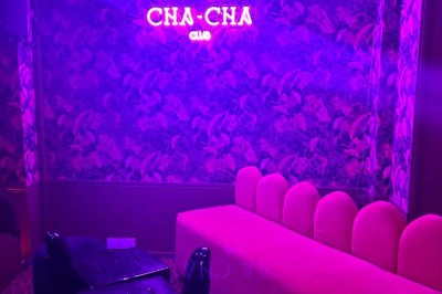 Salle avec bar, banquettes rouges, décor rétro, disques vinyles au mur et éclairage chaleureux.