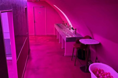 Salle avec bar, banquettes rouges, décor rétro, disques vinyles au mur et éclairage chaleureux.