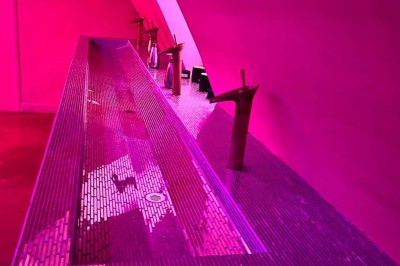 Salle avec bar, banquettes rouges, décor rétro, disques vinyles au mur et éclairage chaleureux.