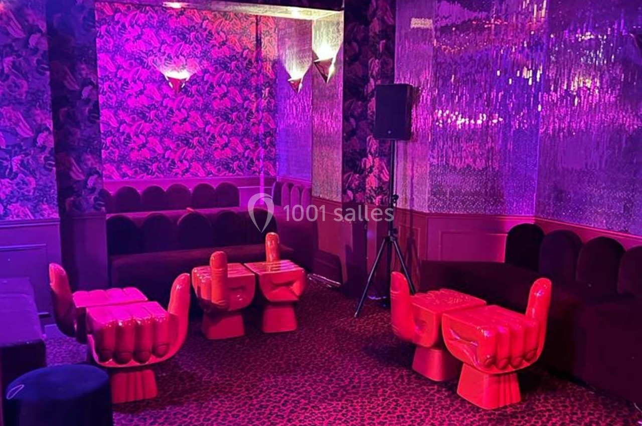 Salle colorée avec des fauteuils en forme de mains rouges, tables assorties et décorations murales à motifs.