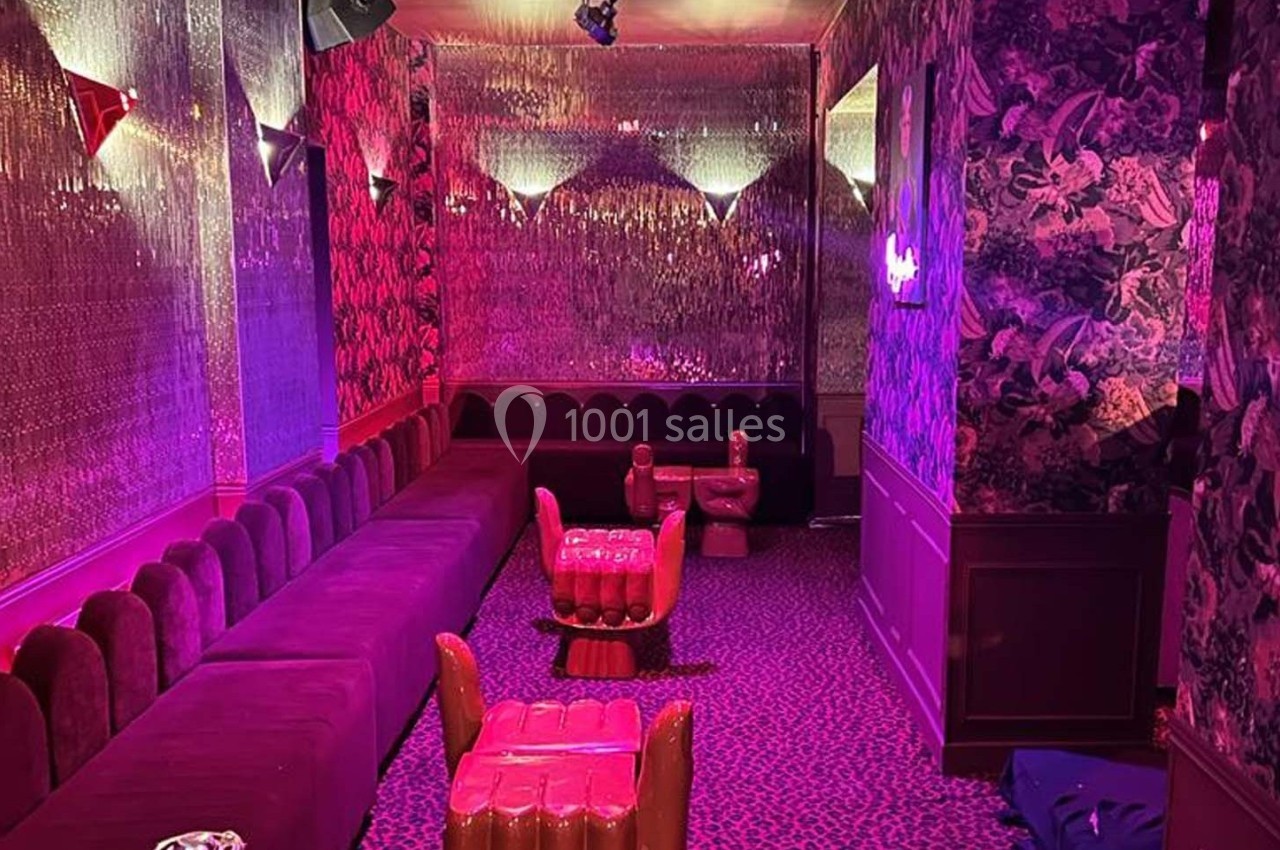 Salle décorée avec des banquettes rouges, fauteuils originaux et éclairage tamisé dans une ambiance rétro et colorée.