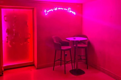Salle avec moquette rouge, banquettes le long des murs, bar en angle et luminaires suspendus dans un décor rétro.