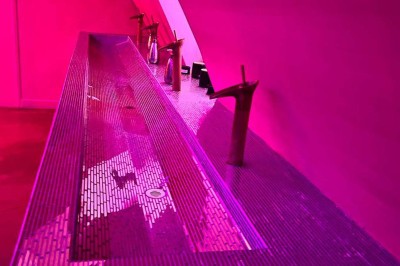 Salle avec moquette rouge, banquettes le long des murs, bar en angle et luminaires suspendus dans un décor rétro.