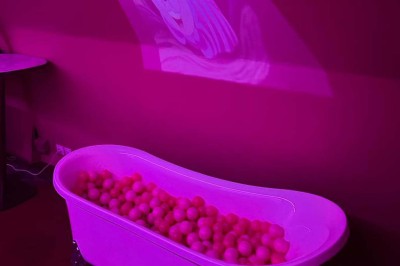 Salle avec moquette rouge, banquettes le long des murs, bar en angle et luminaires suspendus dans un décor rétro.