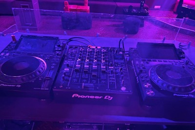 Salle avec moquette rouge, banquettes le long des murs, bar en angle et luminaires suspendus dans un décor rétro.