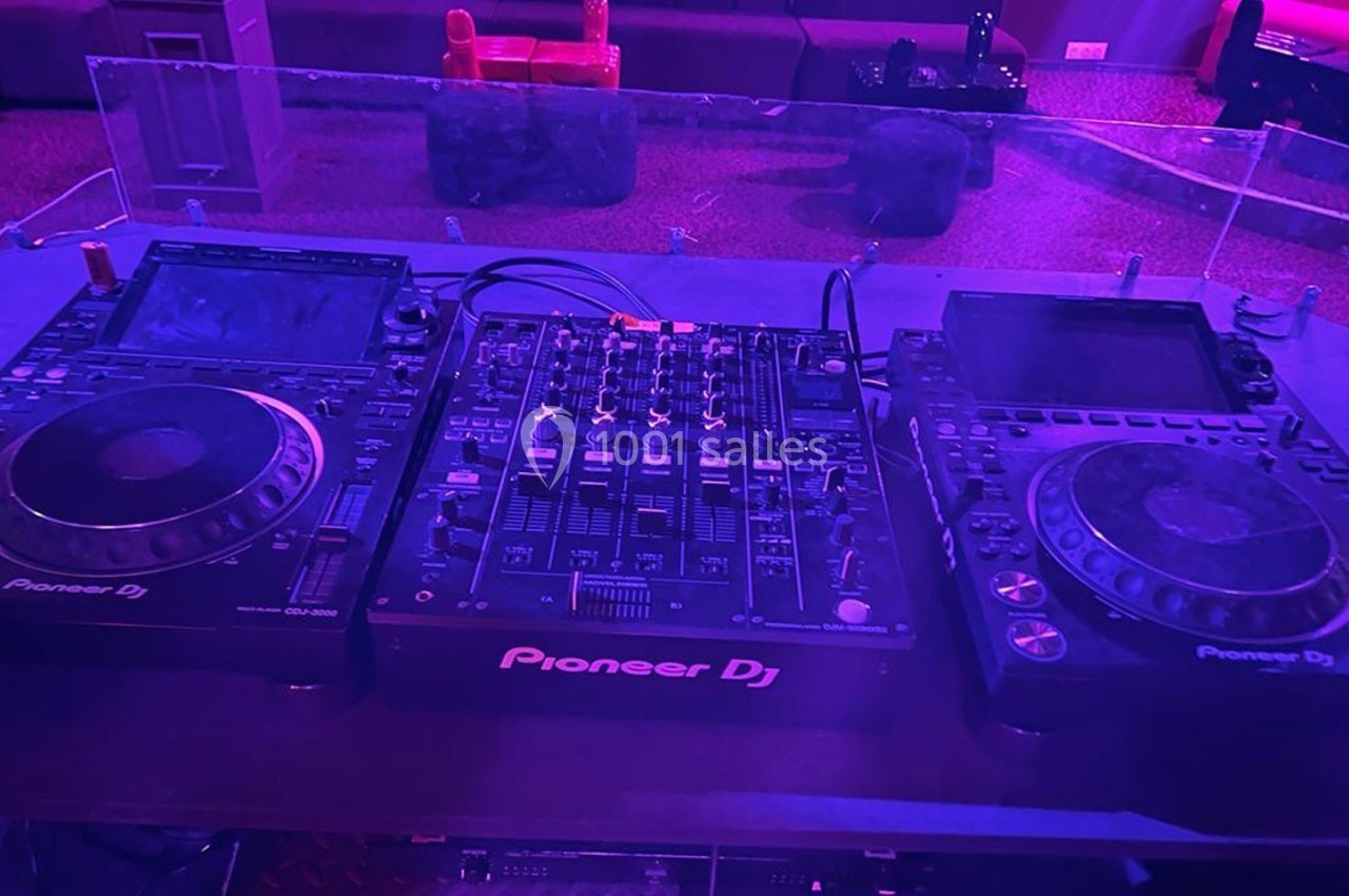 Table de mixage Pioneer DJ avec deux platines et un contrôleur audio dans un environnement faiblement éclairé.